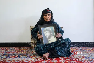 مادر و تنها یادگار از شهیدش-پسر کوچک خانواده که در خرم آباد زندگی می کند تمام یادگاری های شهید را با خود برده تا از آنها مراقبت کند و تنها قاب عکسی از شهید برای مادرش باقیمانده است