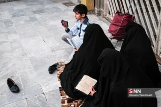 حضور تعدادی از مجاوران روزه‌دار و مغازه داران اطراف حرم مطهر، همزمان با اذان مغرب و لحظه افطار در نزدیکی حرم حضرت معصومه (س)
