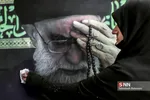 عکس بزرگی از رهبری روی دیوار خانه خانم کاظمی وجود دارد. ایشان در حال تمییز کردن این عکس، قبل از برگزاری مراسم روضه خانگی خود می باشد.