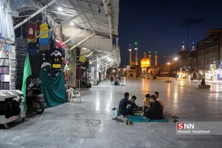 حضور تعدادی از مجاوران روزه‌دار و مغازه داران اطراف حرم مطهر، همزمان با اذان مغرب و لحظه افطار در نزدیکی حرم حضرت معصومه (س)