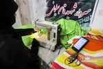 خانم کاظمی در حال دوخت مقنعه برای دختران کم بضاعت است.