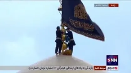 لحظه آویختن کتیبه&zwnj;های عزای سیدالشهدا (ع) در حرم مطهر رضوی (ع) همزمان با برافراشتن پرچم عزا بر گنبد مطهر