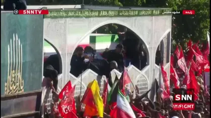 متبرک کردن پارچه و چفیه با تابوت پیکر رهبر شهید در مشهد